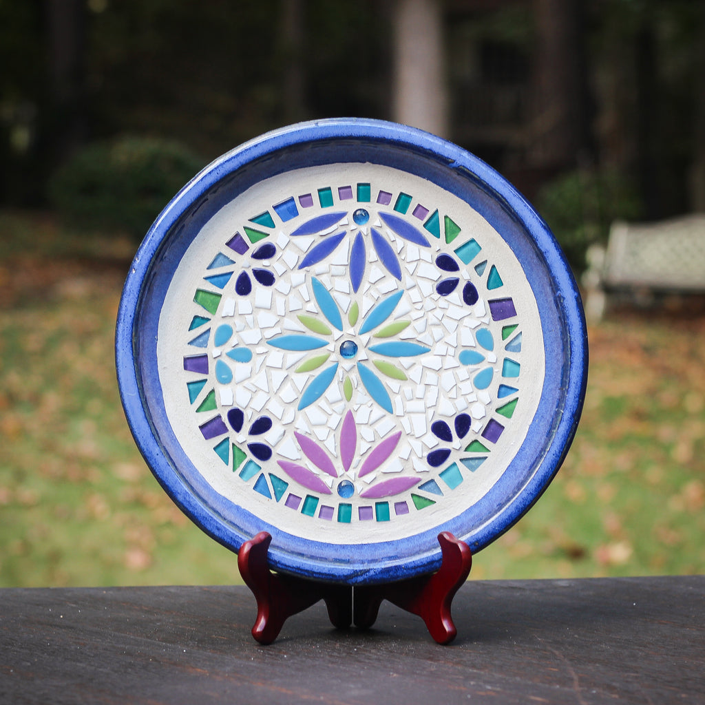 Decorative mosaic plate with colorful patterns on a stand outdoors